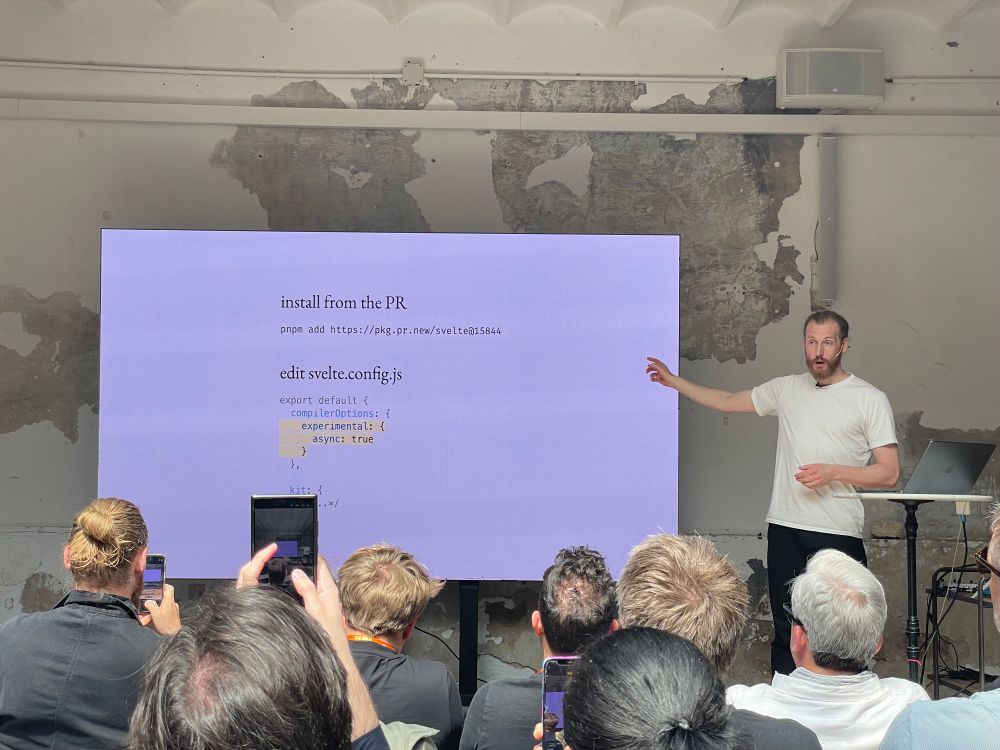 Photo of Rich Harris introducing the Pull Request for the new async API / pattern proposal.
The slide says:

# install from the PR
pnpm add https://pkg.pr.new/svelte@15844
# edit svelte.config.js
export default {
  compilerOptions: {
    experimental: {
      async: true
    }
…
}