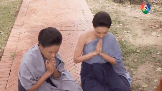 two people praying on a brick walkway with a channel 7 logo visible in the background