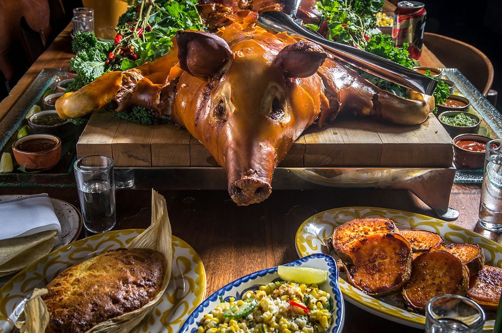 face-to-face with a roasted pig splayed on an elevated board surrounded by condiments and side dishes