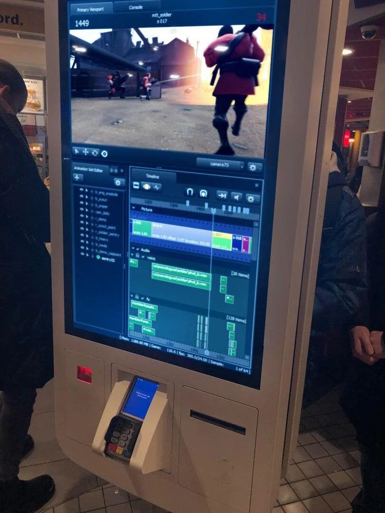 Photo taken at a McDonald's restaurant showing a touch-screen ordering kiosk. The kiosk displays the user interface for Source Filmmaker with viewport showing a scene set in a Team Fortress 2 level using the Soldier character and an explosion. A timeline window can be seen below the viewport. 