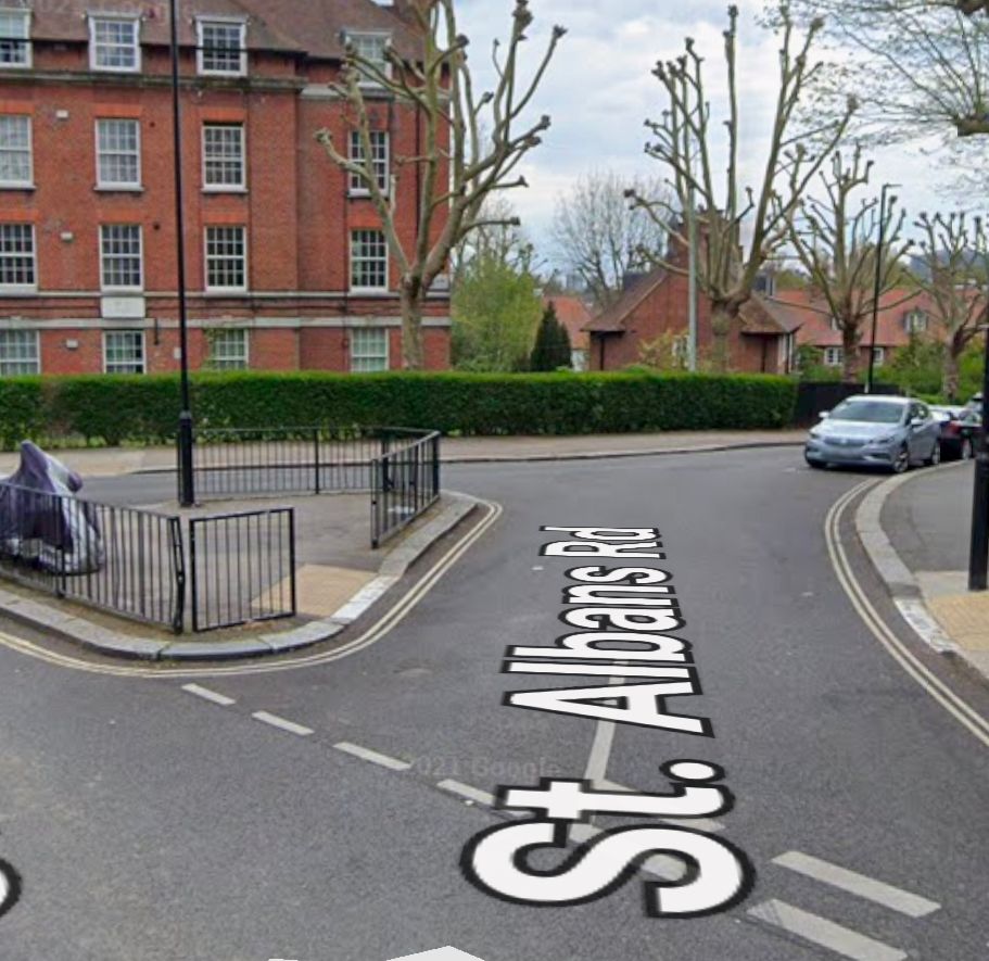 Google Streetview screenshot showing a street junction with lots of tarmac, railings and no greenery 