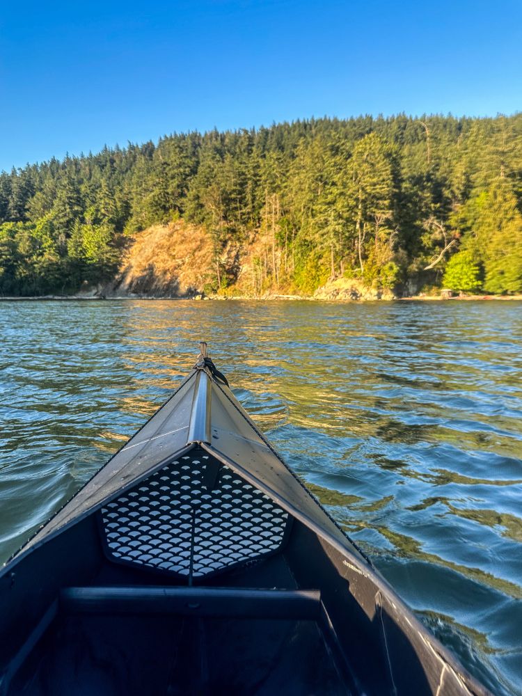 Kayak on a lake with trees and blue sky in the back 