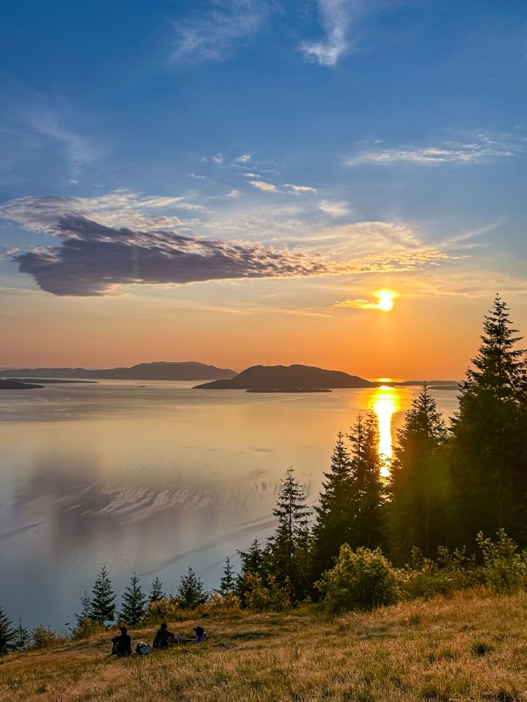Sunset over an lake with some red wood trees in the front 