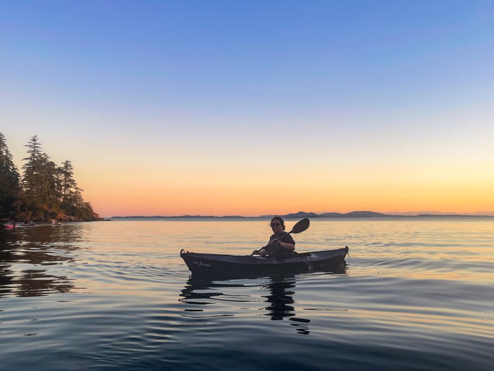 Me paddling my kayak on the lake with sun setting in the background 