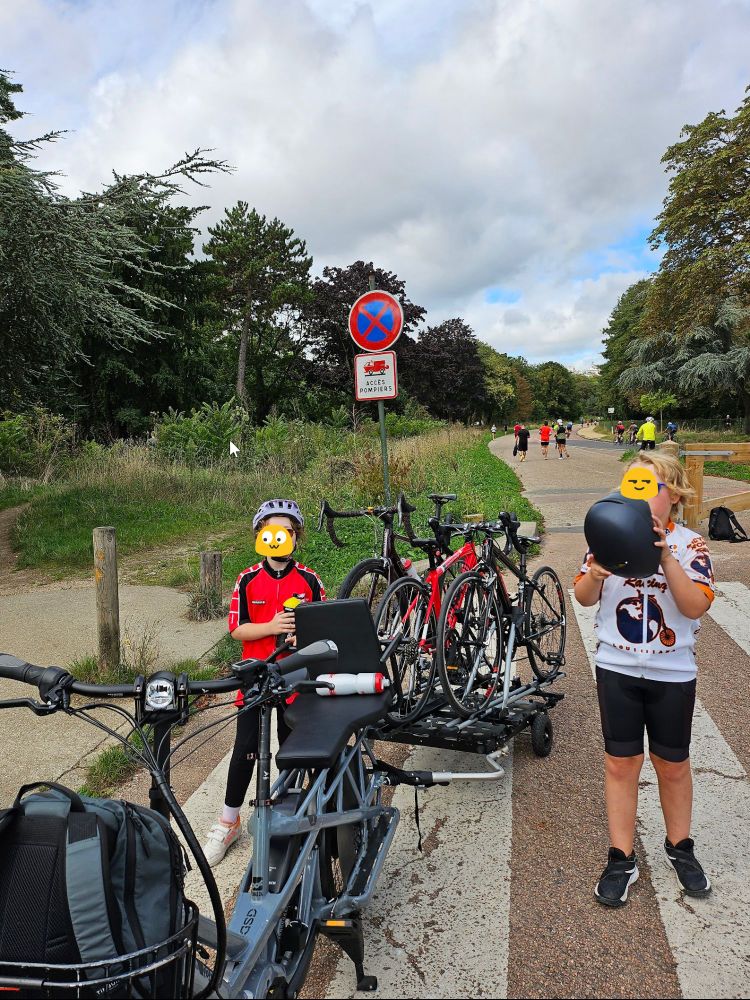 e-bike with 3 road bikes on a trailer and two kids standing on either side