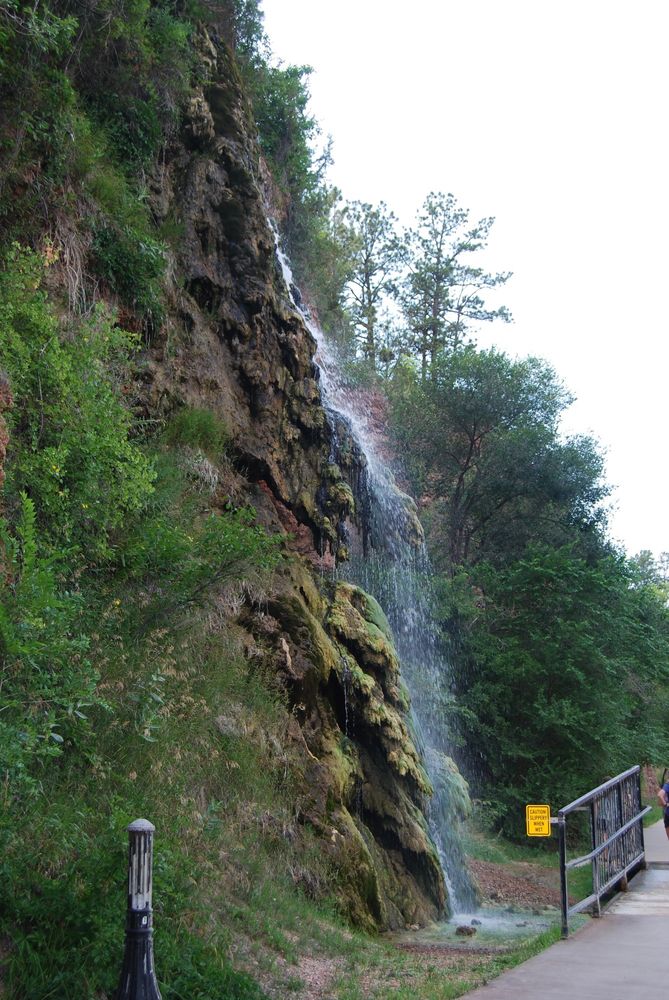 The waterfall tumbles down several levels of rock and soil. A walkways runs at its base.