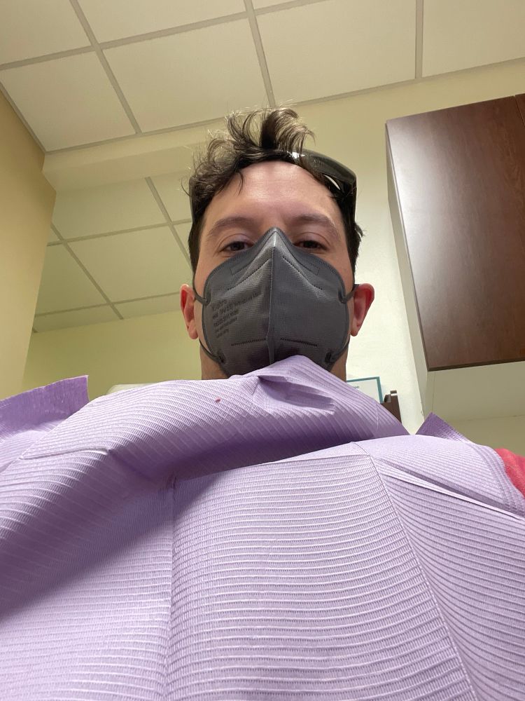 Tired man in a KN95 for easy removal during dental cleaning. 