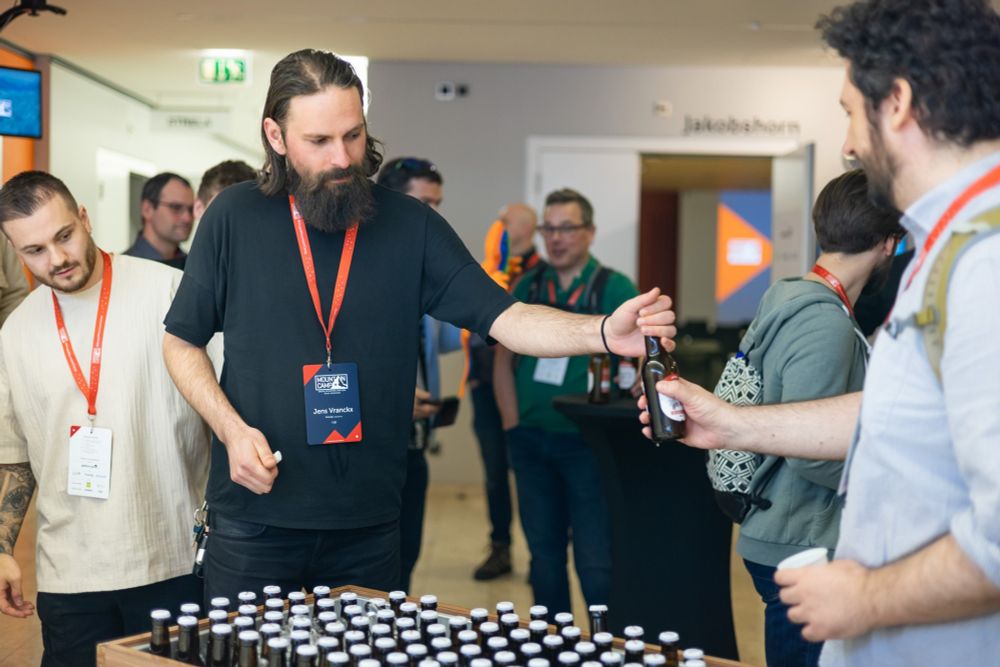 Promotional graphic for MountainCamp 2025 | Organizer, Jens Vranckx handing out beers at MountainCamp 2024 to the attendees.
