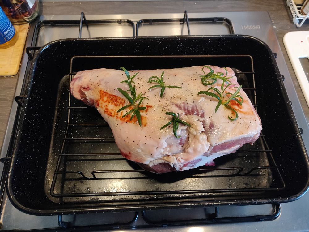 A salt marsh lamb leg with rosemary and garlic in a roasting tin ready to go in the oven 