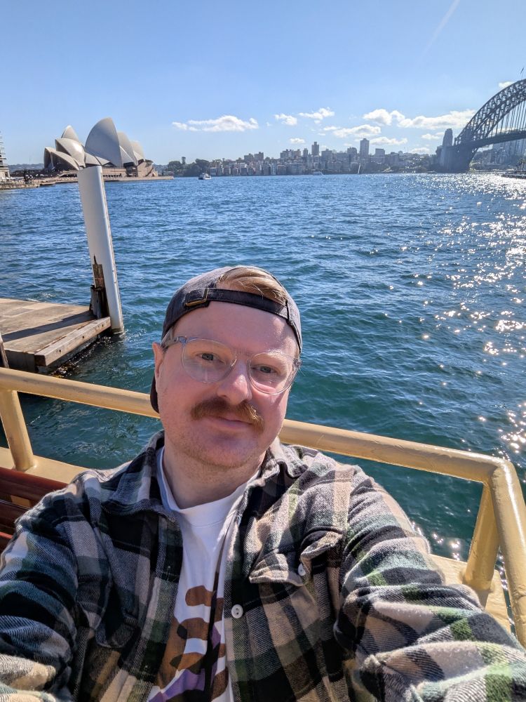 A selfie taken on a ferry, docked at Circular Quay. The Sydney Opera House and the Sydney Harbour Bridge are behind me.