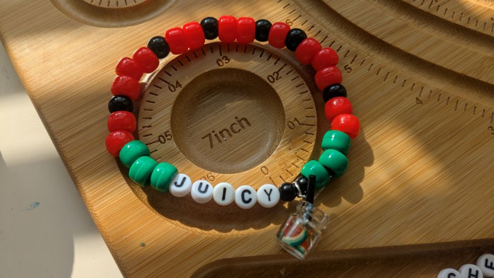 a kandi bracelet themed off watermelon that says juicy