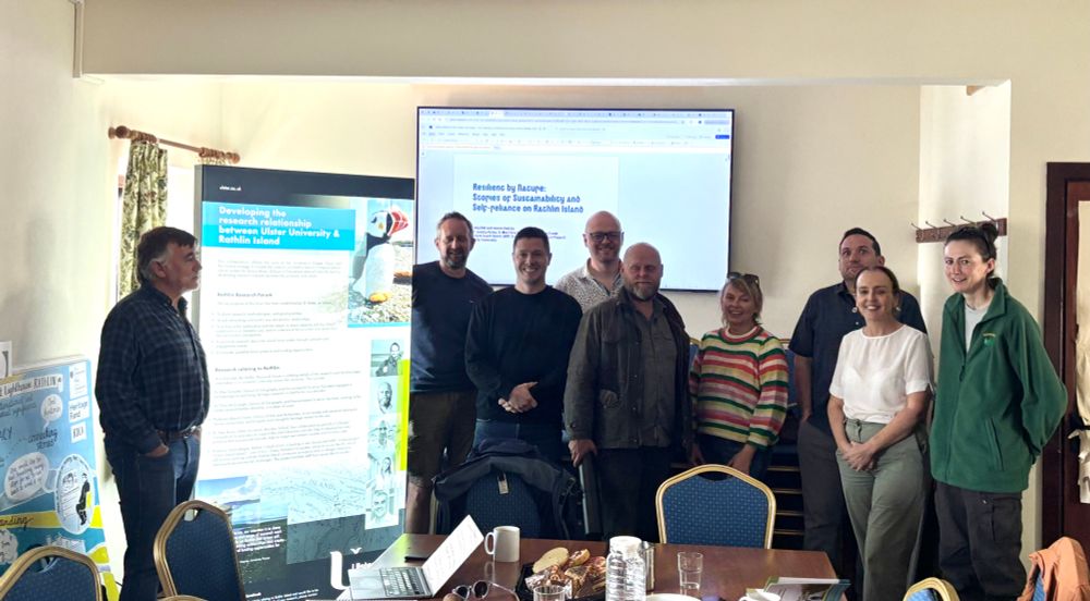 A photograph showing some of the UU staff and Rathlin Community Development worker with displays about some examples of Rathlin research.