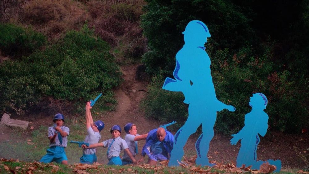 Image du film, avec des adolescents en bleu qui prennent des positions débridées en tenant des flingues en plastique bleu.