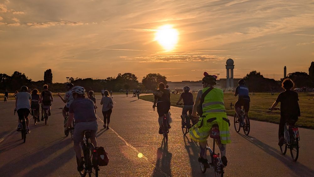 Menschen fahren mit dem Rad auf dem Tempelhofer Feld in den Sonnenuntergang 