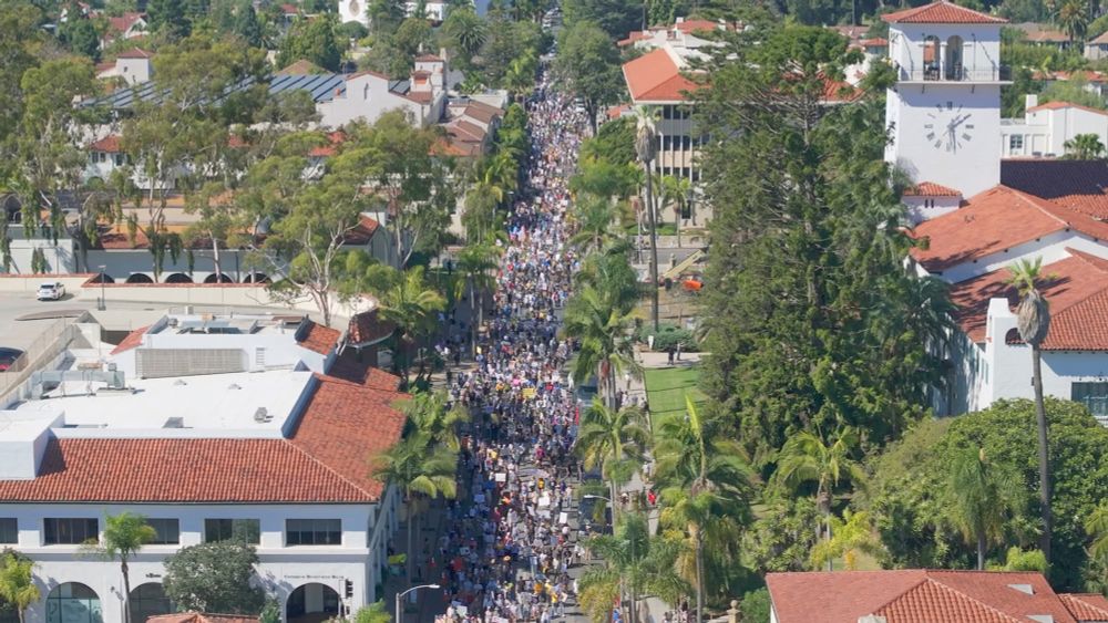 13,000 people fill the streets in an aerial shot of Santa Barbara, with green trees and red tile roofs.