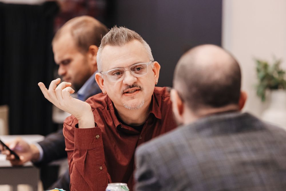 H-Net Executive Director, Jesse Draper, talking with another man at a conference.