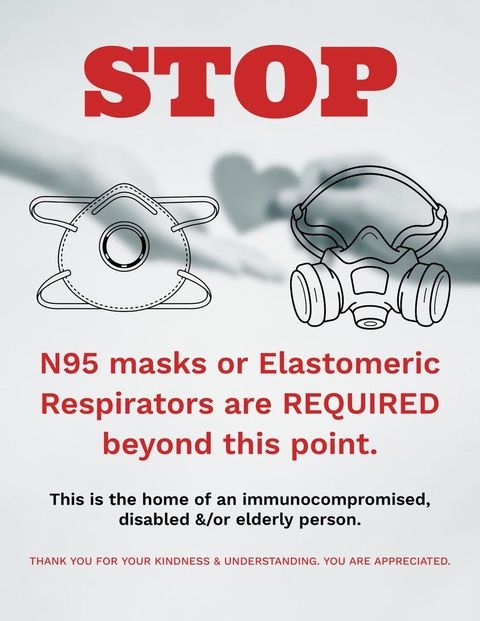 A door sign stating that wearing an N95 or Elastomeric respirator is required to enter.