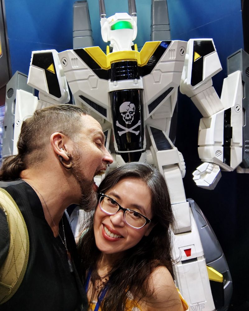 Photo of two people in front of the Skull Leader veritech from Robotech.