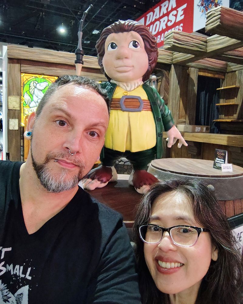 Photo of two smiling people in front of The Hobbit statue.