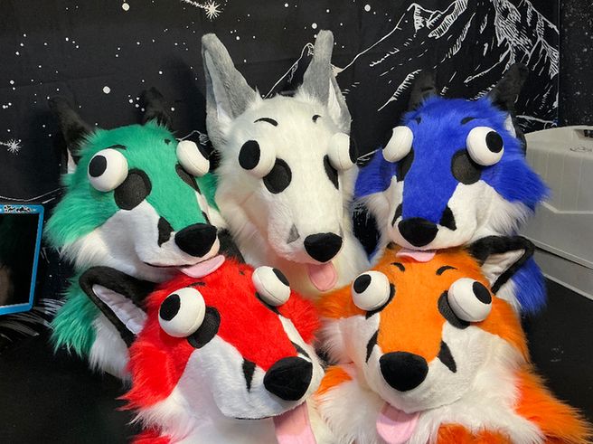Some very derpy looking fox heads arranged in a pile. There is teal, white, blue, red, and orange!