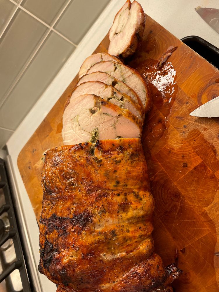 The same turkey breast roast, now sliced open, revealing it had been wrapped around a pesto-based sauce, now running through what had been interstices of the wrapped roast.