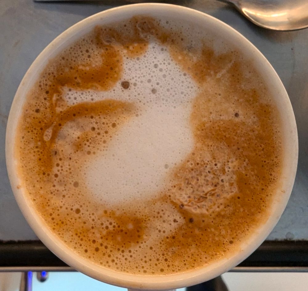 Foam on top of a coffee cup that looks like a seahorse 