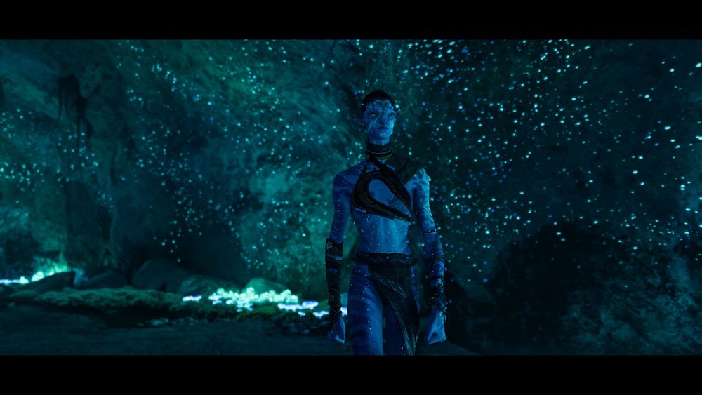 Seyko walking through a cave that is speckled with bioluminescence, making the cave walls look like they’re covered in stars. she’s walking very confidently with her hands balled up in fists
