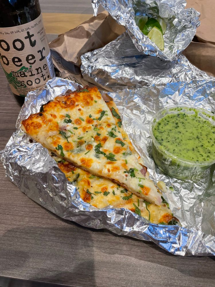 A photo of two slices of pizza and green sauce 