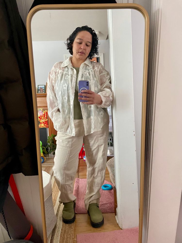 Wearing white jeans with a sheer, floral cream blouse. 