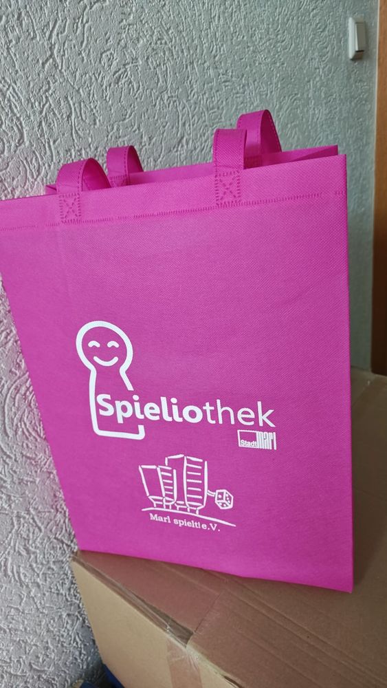 Tragetasche in Fuchsia mit weißem Logo der Spieliothek und des Vereins Marl spielt