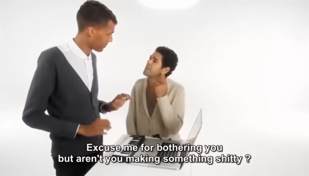 Music producer Stromae, working on a laptop. Comedian Jamel Debbouze approaches and asks "excuse me for bothering you but aren't you making something shitty?"