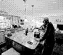 Highly dithered black and white photo of a man standing at a kitchen island 