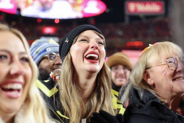 taylor smiling at Travis giving a speech at the afc championship 