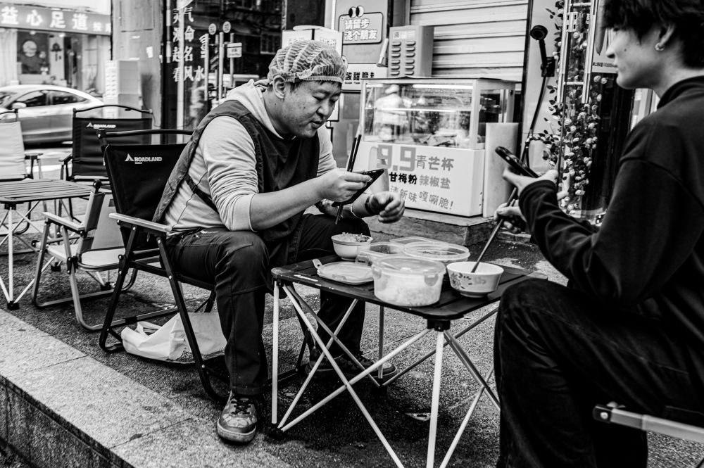 The chef is having breakfast on the street before the lunch business starts. 