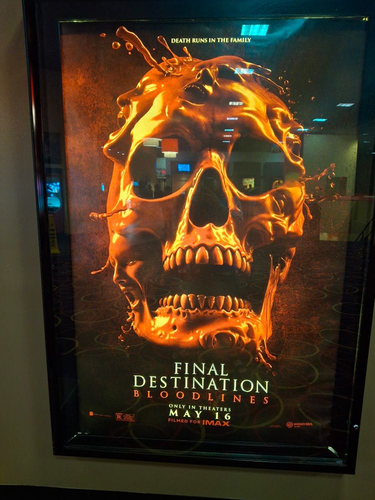 A photo of a promotion poster for Final Destination Bloodlines depicting a skull covered in blood, shaped with screaming faces made out of said blood all around it.