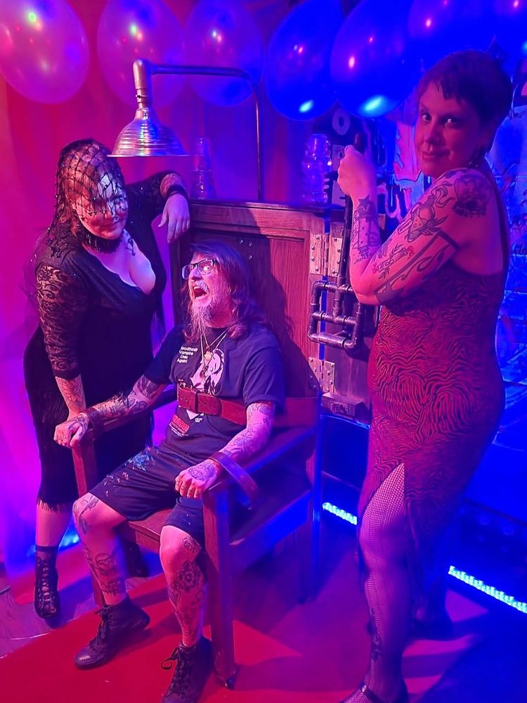Me in the electric chair, surrounded by 2 beautiful women.