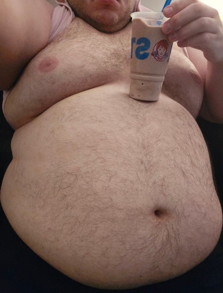 Photo of my chest and belly with my shirt lifted up. A large frosty from Wendy's is resting on top of my belly
