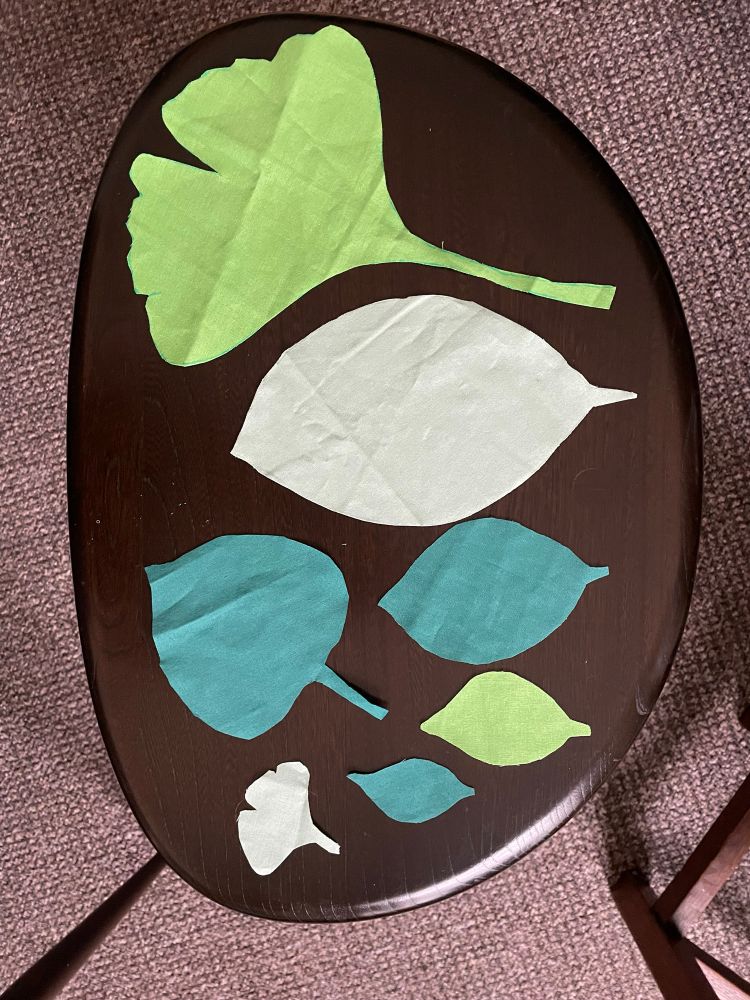 Various leaf shapes in three shades of green cotton fabric, laid out on a coffee table.