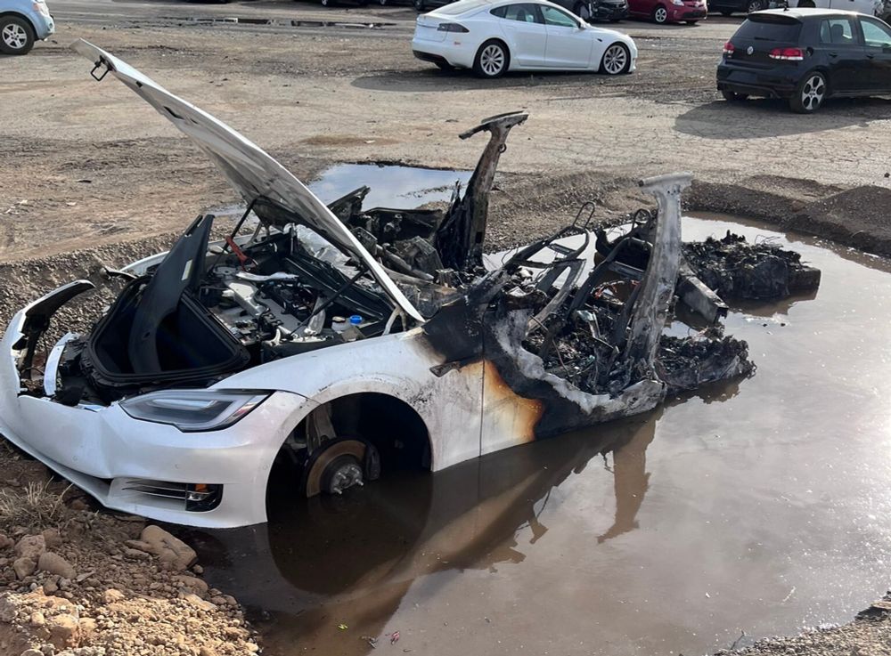 Burnt out Tesla car in a puddle of water
