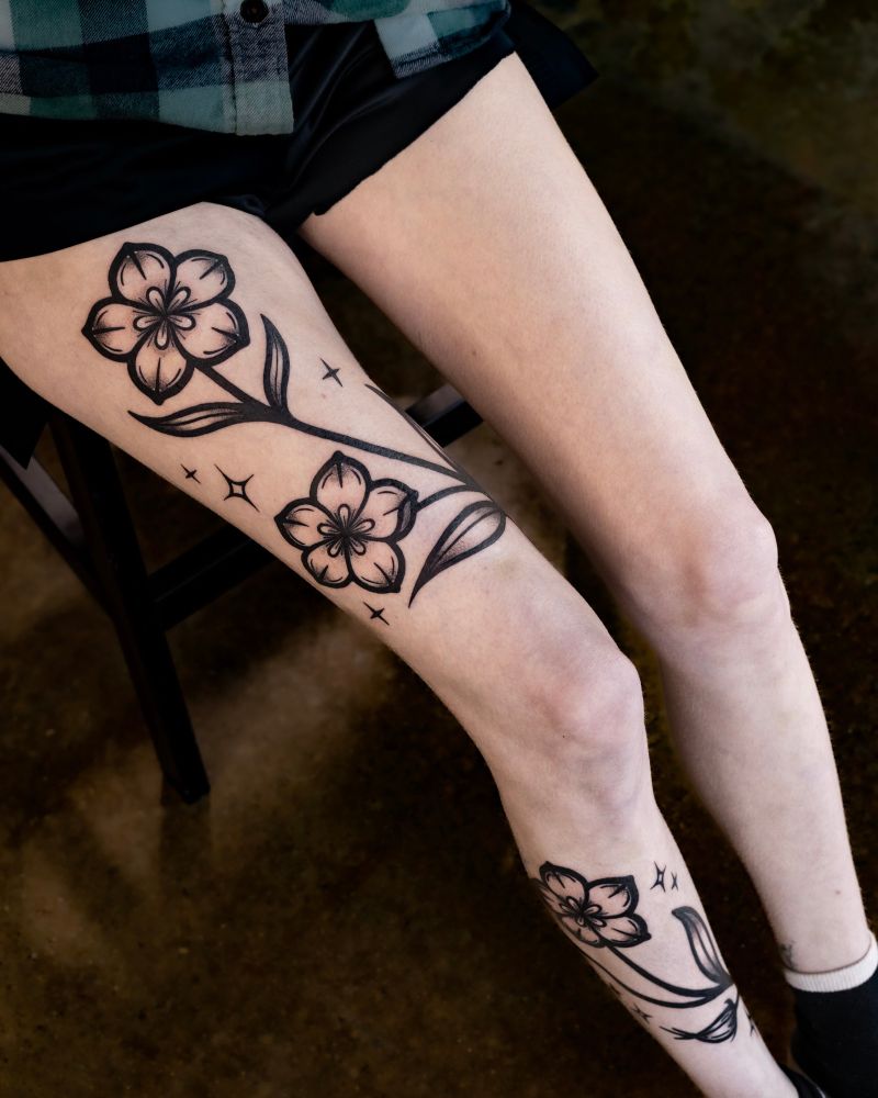 Photo of a person sitting down, with a large tattoo of prairie gentian flowers wrapping around the entire length of their right leg. 