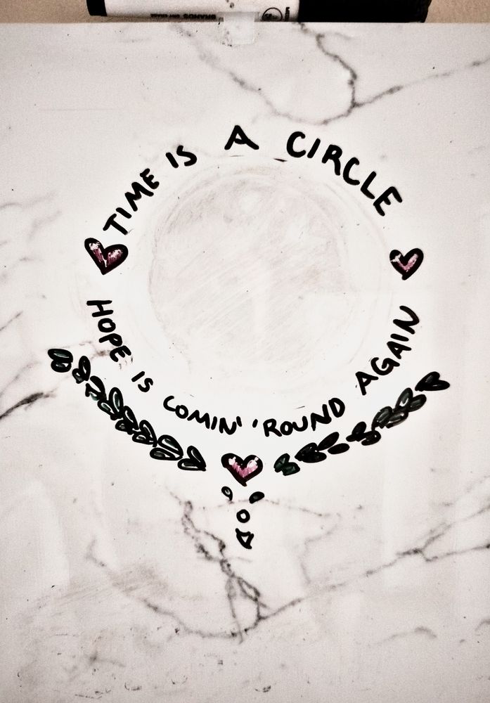 a whiteboard doodle that reads "time is a circle, hope is coming' 'round again"