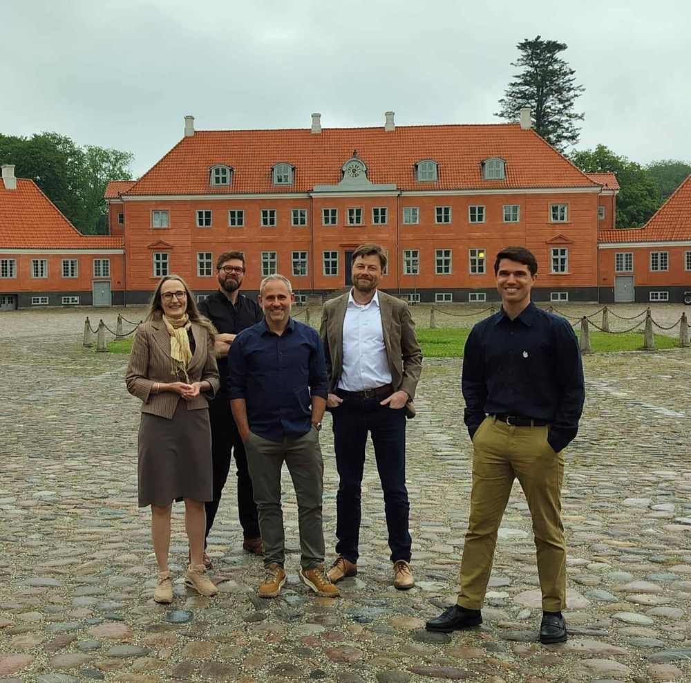 A photo of five people standing in front of a red brick building 