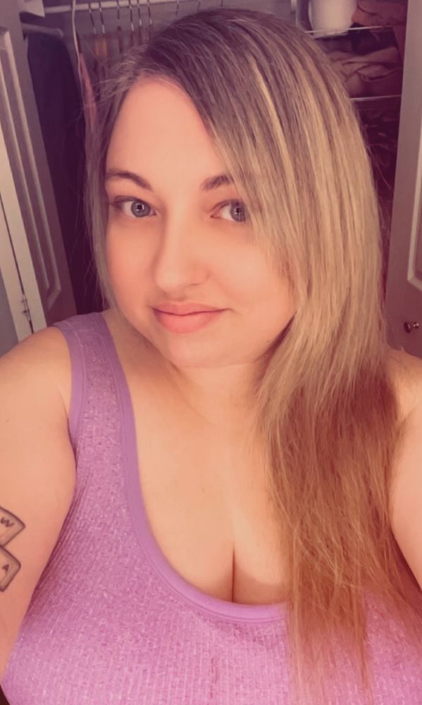 A selfie of Lorelei in a lavender crop top. Her head is turned slightly to the side to show off her side bangs