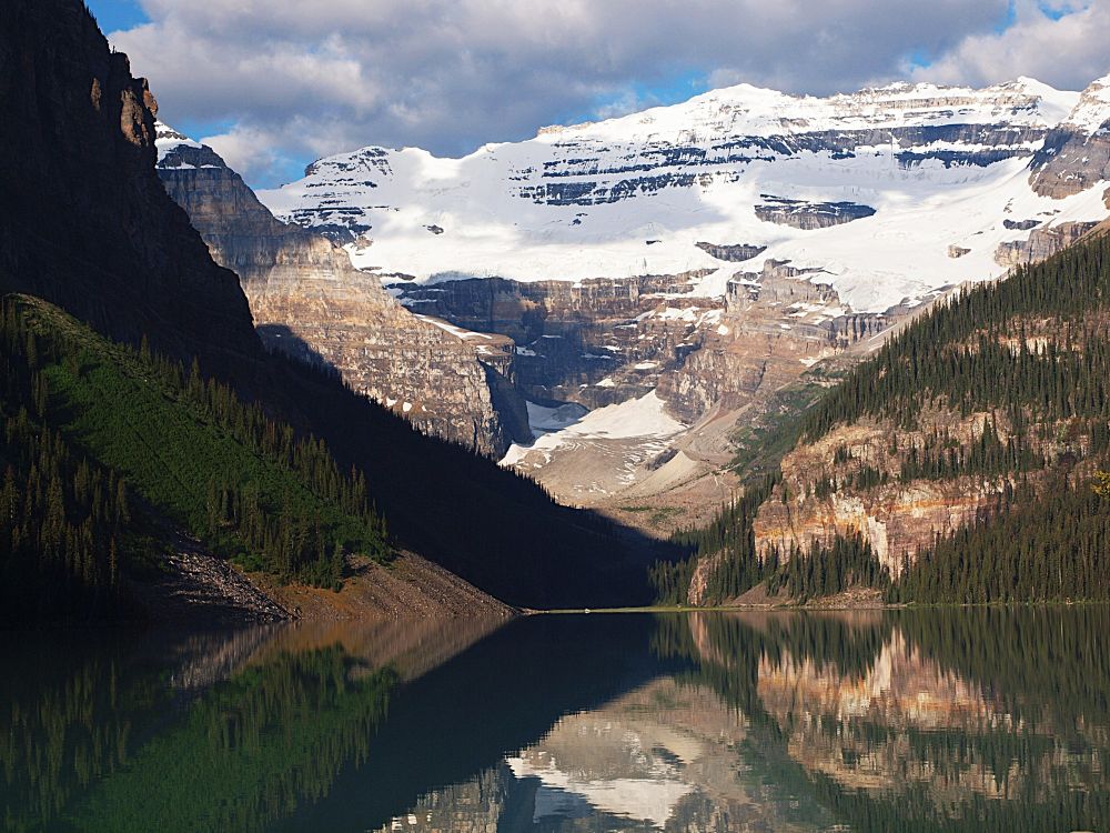 Lake Louise. Alberta, Canada. White capped mountains and pine forest reflect off the lake.
