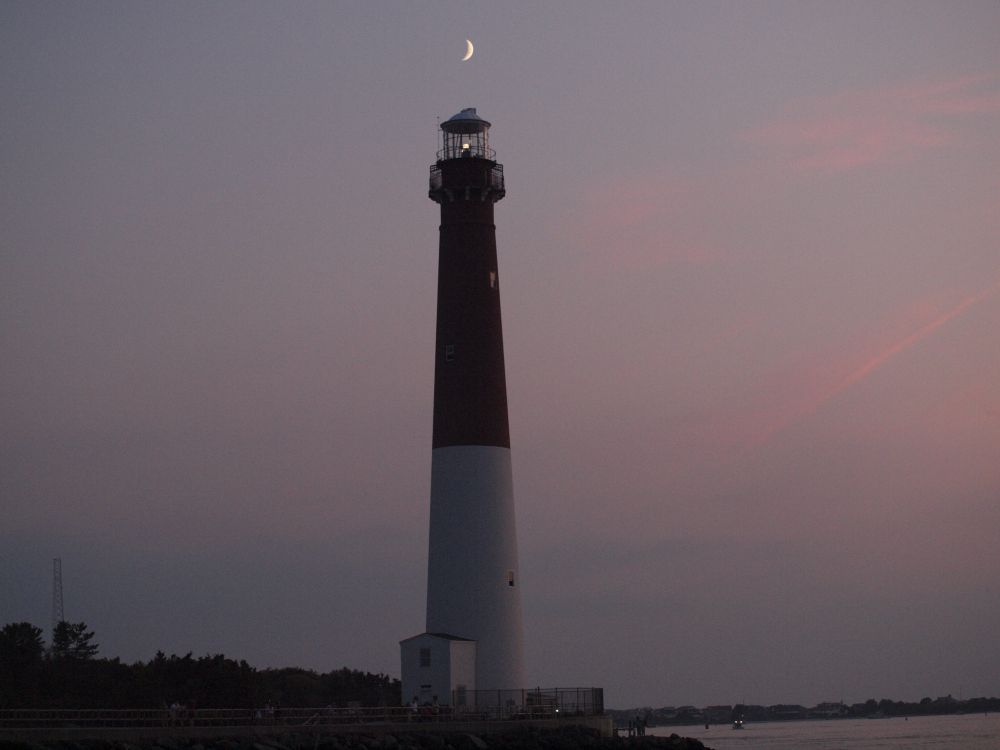 A half-moon hovers directly over Barnegat Lighthouse. Long Beach Island, New Jersey. 