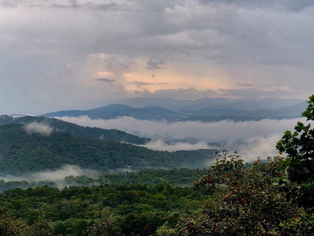 Rainy morning with a bright patch trying to break through. Low hanging clouds enswathe trees in the valley.