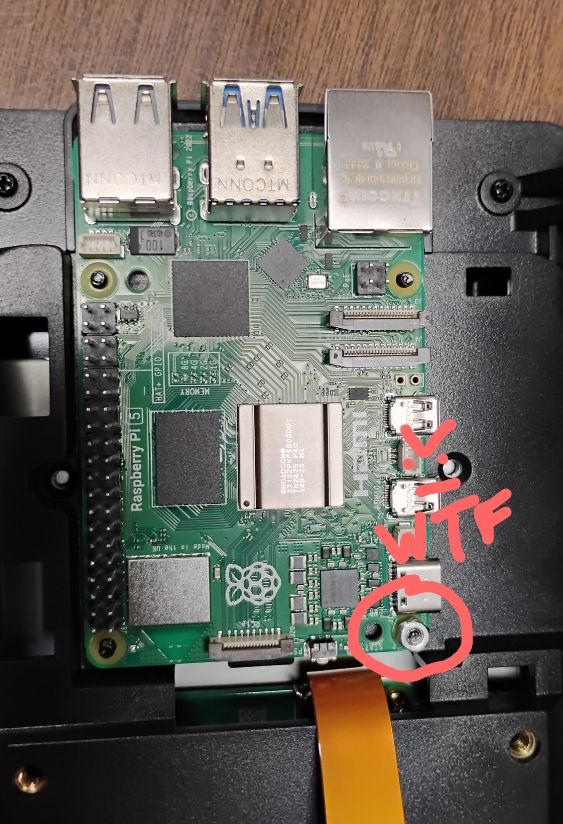 A photo of a Raspberry Pi 5 single-board computer being installed in a SmartiPi 7" screen housing, showing the complete lack of room left for the assembler to tighten the nuts that secure the Pi board, forcing you to use incorrect tools like needlenose pliers to tighten, risking rounding out the cheap aluminum nut or slipping with the pliers as pressure is applied, risking damage to nearby sensitive components. No, standoffs are not an option since the designers, in their infinite wisdom, also saw fit to make the edge profile of the cover too damned short to allow you to use them, and even still having to trim off the post guards so they fit properly. This product has been around for literal years and still suffers from the same problems. Raspberry Pi Foundation should be ashamed and stop sponsoring it. 