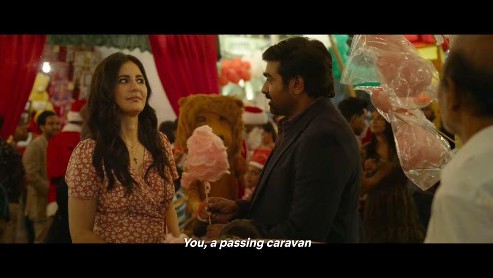 Setting is a carnival. Indian man holds pink candyfloss whilst an Indian woman looks at him sceptically.