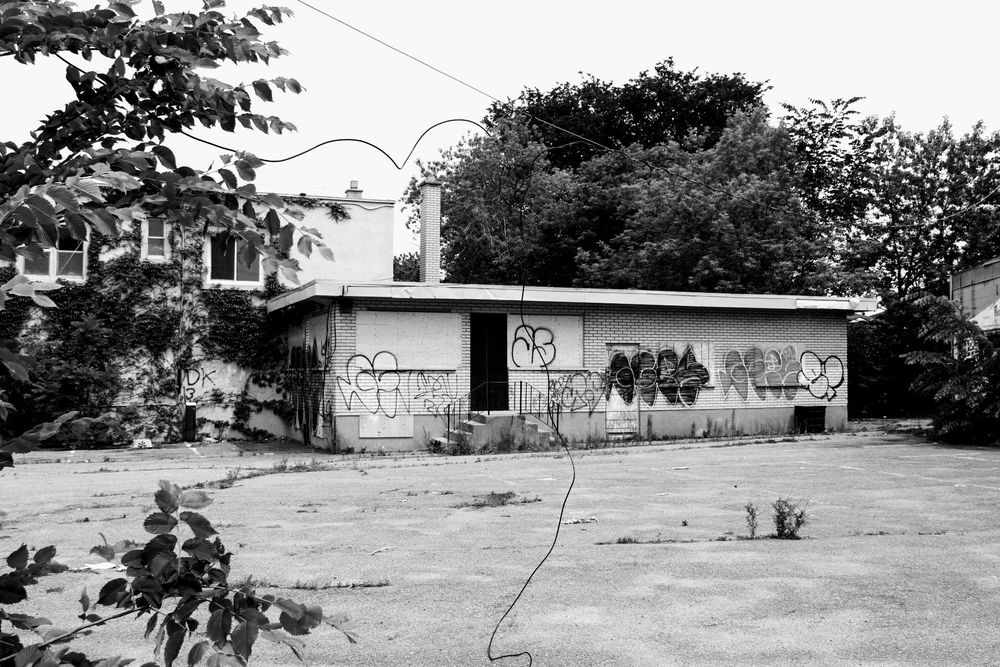 Black and white photo of abandoned buildings covered in graffiti 