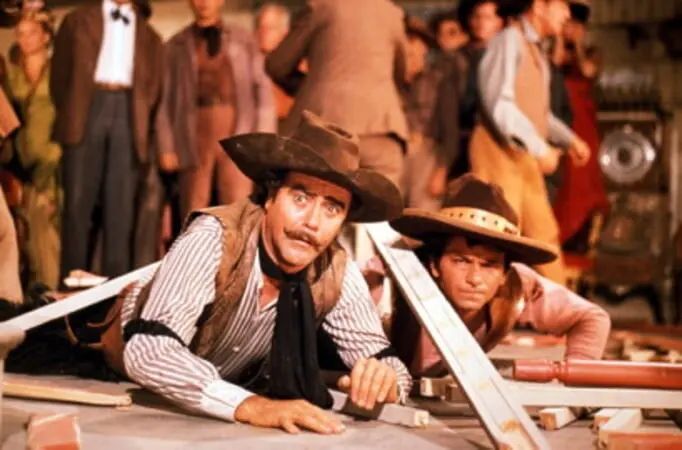Jack Lemmon as Professor Fate in THE GREAT RACE, in the Western bar brawl scene, lying on the floor, looking confused, with a broken board over his head. He wears a vest, striped shirt, black kerchief and cowboy hat